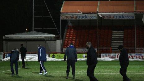 Crawley groundstaff inspect the pitch after the postponement