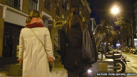Two girls walking along a street at night