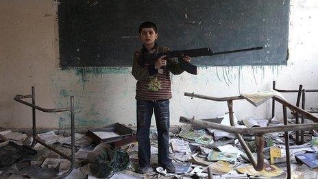 Boy with a toy gun in damaged school in Deir al-Zor, Syria