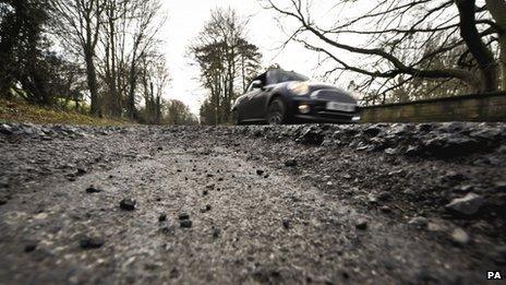 A car on a heavily potholed road in Gloucestershire