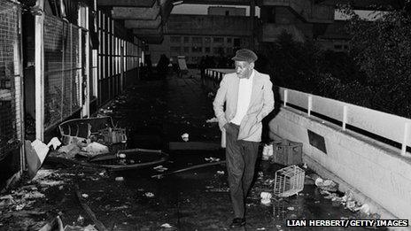 A man picks his way through the debris on a walkway on the Broadwater Farm housing estate