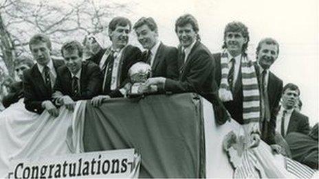 Members of the triple winning team celebrate on an open top bus