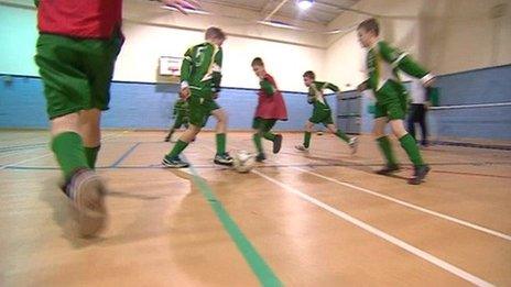 Boys playing football in a gym