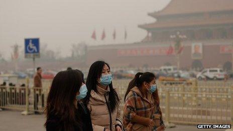 Three women in facemasks in China in front of a temple