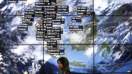 A lady stands in front of an electronic display showing live information of flight positions according to predicted time and flight duration calculations at the Kuala Lumpur International Airport