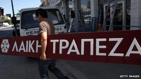 Worker carrying a Laiki Bank sign, in May 2013