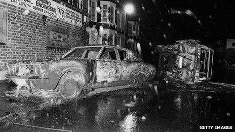 Cars left overturned and burned-out in the street after rioting on the Broadwater Farm housing estate