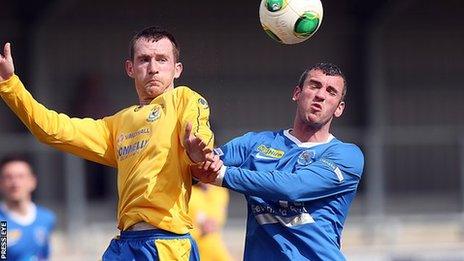 Dungannon's Dermot McCaffrey challenges Ballinamallard player Ryan Campbell