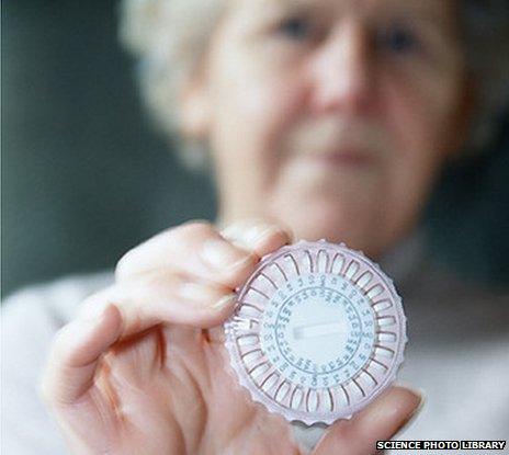 An elderly woman holding up a pill dispenser