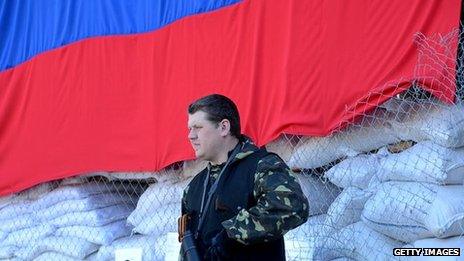 An armed man stands guard outside a building seized by pro-Russia separatists in the eastern Ukrainian city of Slavyansk on April 25, 2014