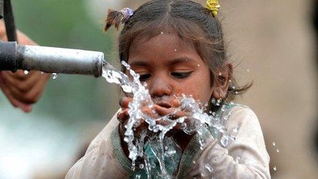 A young Pakistani girl drinks from a hand pump in Lahore