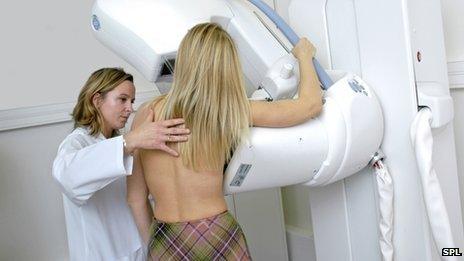 Radiographer preparing a woman for a mammogram