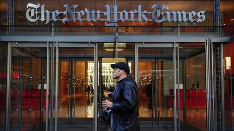 Man walking by the exterior of the New York Times building