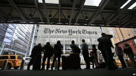 Pedestrians wait for taxis across the street from The New York Times in New York, 14 May 2014