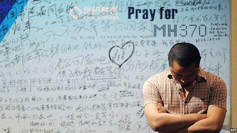 A man stands at a memorial wall for MH370