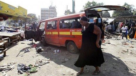 A woman walks past a damaged vehicle near the site of the explosion in Nairobi (16 May 2014)