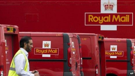 A Royal Mail worker walks past a group of delivery vans