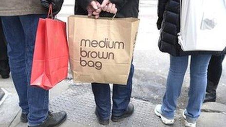 Shoppers in New York waiting to cross the sidewalk clutching their shopping bags