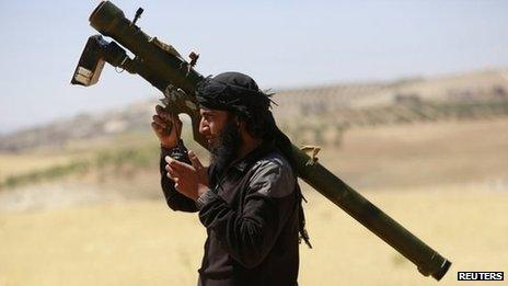 An Islamist Syrian rebel group Jabhat al-Nusra fighter talks on a walkie-talkie while carrying his weapon in northern Idlib province, 17 May 2014