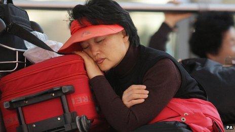 A passenger enduring a long delay at Terminal 5 rests in the departure lounge