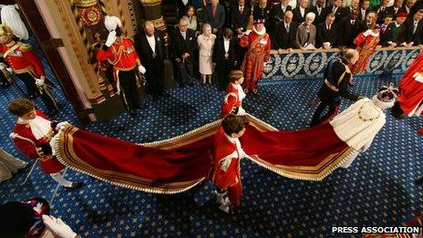 Three pageboys hold the train of the Queen's gown as she leaves