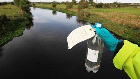 An Environment Agency worker holds a sample bottle of water from the River Trent at the time of the leak