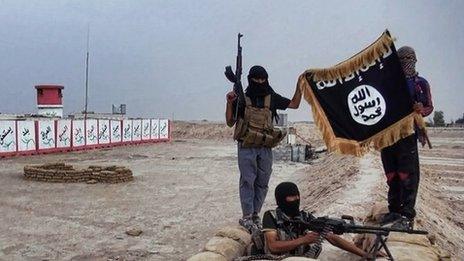 ISIS militants pose with a Jihadist flag at an Iraqi army checkpoint in the northern Iraqi province of Salahuddin (11 June 2014)