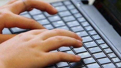 A young teenager types on a computer keyboard