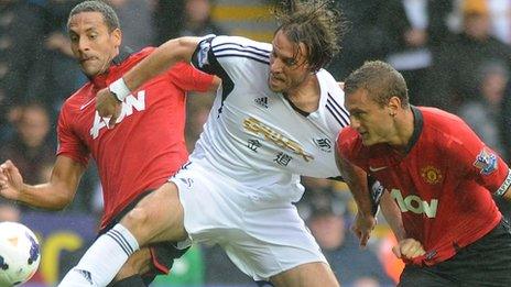 Michu battles for the ball with Rio Ferdinand and Nemanja Vidic of Manchester United