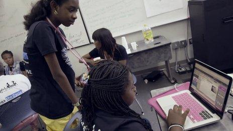 A student at her computer with someone looking over her shoulder