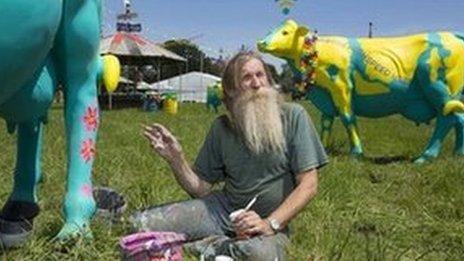 Artist Hank Kruger putting the finishing touches to a herd of fibreglass cows at Glastonbury festival