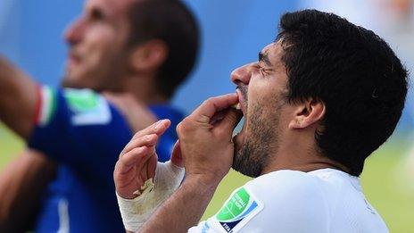 Luis Suarez holds his mouth after clashing with Girgio Chiellini