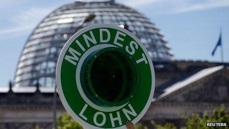 A campaigner holds a sign in front of the Reichstag, demanding a minimum wage