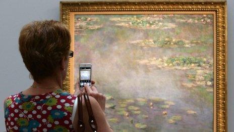 Woman taking picture on phone of art