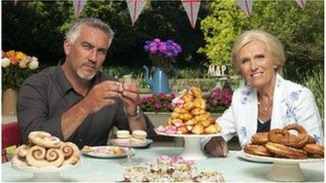 Paul Hollywood and Mary Berry at a table piled high with cakes