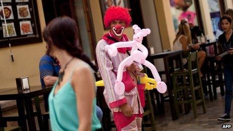 David (C), unemployment for one year, dresses as a clown and busks on the street in a bid to survive economically in Malaga