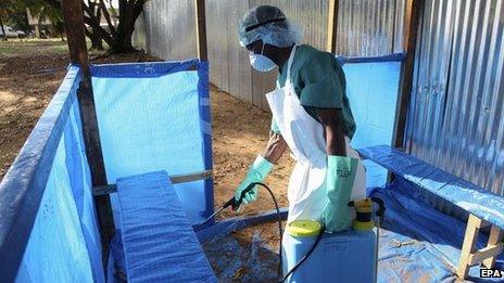 A nurse sprays disinfectant at an isolation unit in Liberia