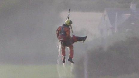 An RAF Valley helicopter crew member rescues one of the men