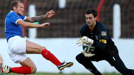 Linfield player-manager Warren Feeney stretches as Glentoran goalkeeper Elliott Morris gathers the ball