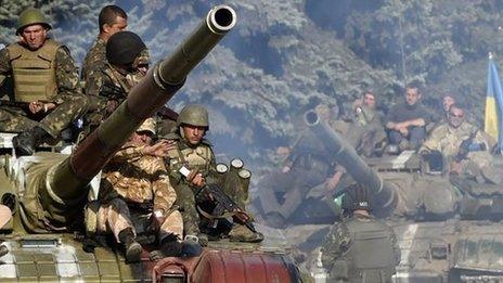 Ukrainian army soldiers ride a tank on a road near where pro-Russian separatists fired heavy artillery, on the outskirts of the key south-eastern port city of Mariupol, on September 5