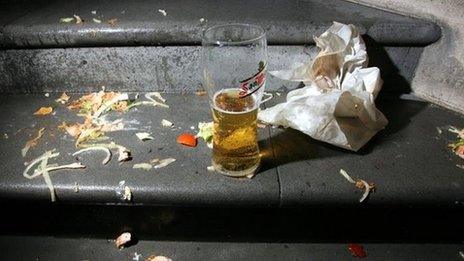 Discarded takeaway wrapper with a pint of lager, left on steps