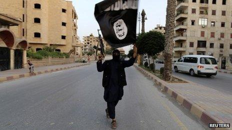 Islamic State fighter waves an IS flag in Raqqa, Syria - June 29, 2014