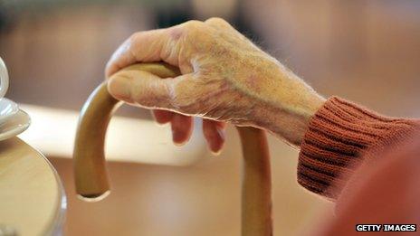 Close up of an elderly person's hand holding a walking stick