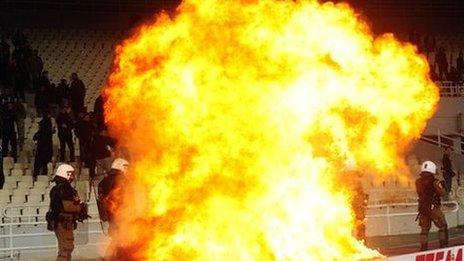 Greek riot police watch a fire set off by a petrol bomb as they clash with Panathinaikos supporters during a Greek Super League football game against Olympiakos in Athens in March 2012