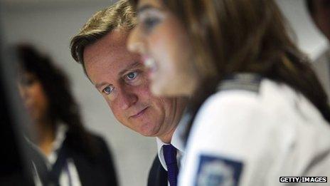 Prime Minister David Cameron watches security monitors as he talks to UK border agency officials