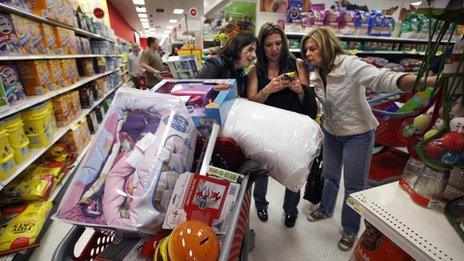 three women looking at a smartphone next to a shopping cart