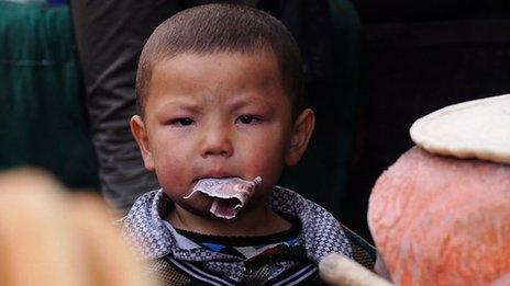 An Uighur child with money in his mouth