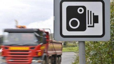 A lorry driving past a speed camera sign