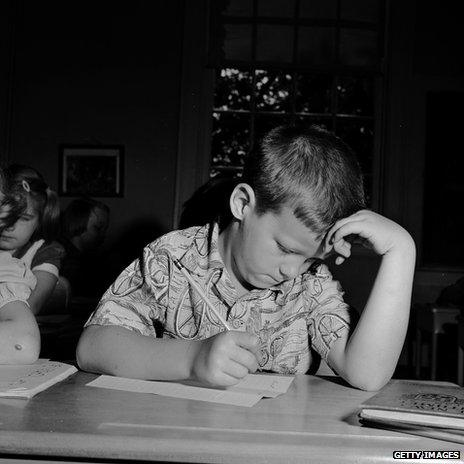 An American schoolboy puzzling over a maths test in 1955