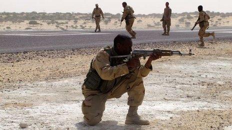 One soldier holds a gun with others behind him run